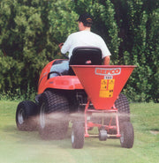 BEFCO spreader in action, attached to a lawn tractor, distributing material evenly across a grassy area