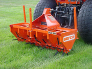 BEFCO core aerator attached to a tractor, operating on grass, showcasing its sturdy steel construction.