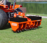 BEFCO core aerator attached to a tractor, operating on a grassy field by a lake, showcasing field use.