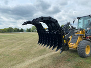Angled black Stinger Attachment clam grapple attached to Yellow John Deere Tractor and operator