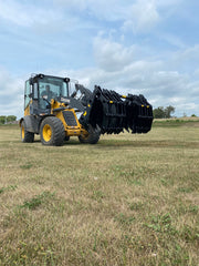 Yellow John Deere tractor with closed black Stinger attachment claw angled down