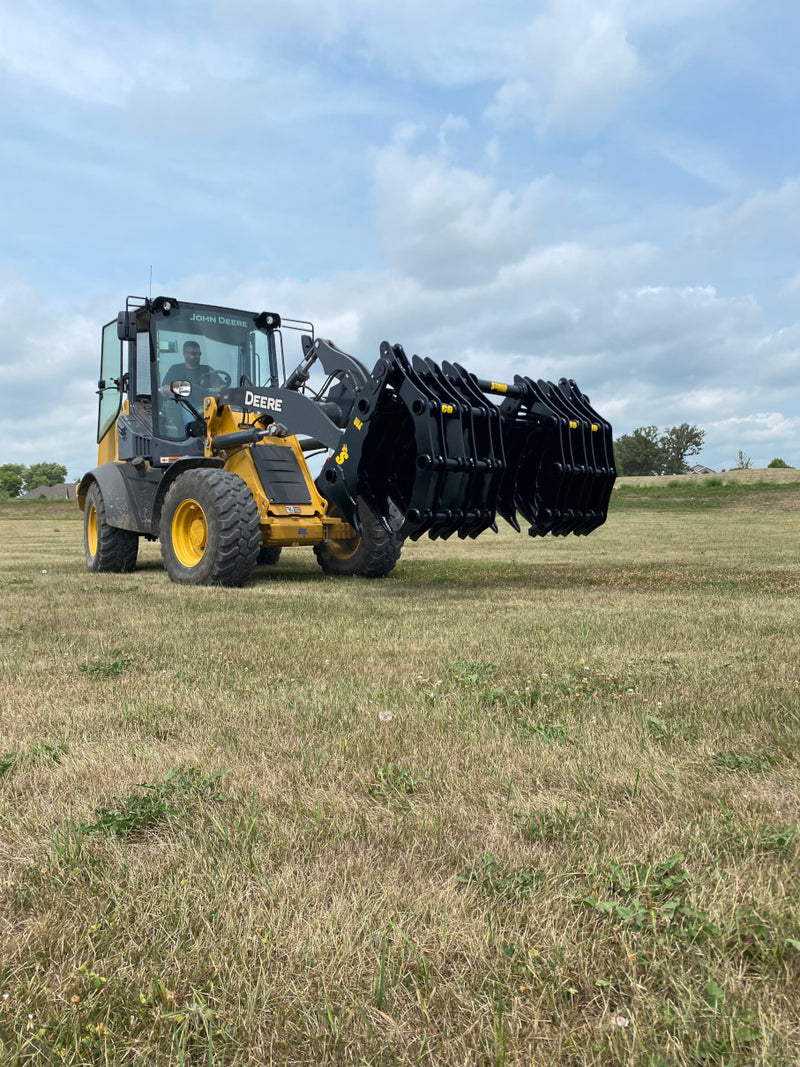 Yellow John Deere tractor with closed black Stinger attachment claw angled down