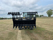 Open black Stinger Attachment claw attached to John Deere Tractor and operator