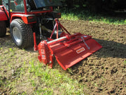 BEFCO rotary tiller attached to a tractor, efficiently tilling soil in a field, demonstrating practical use.