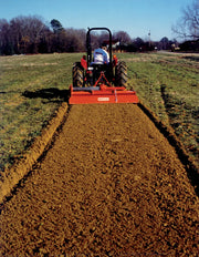 Tractor using BEFCO TILL-RITE T60 rotary tiller on field, creating smooth soil path, rear view