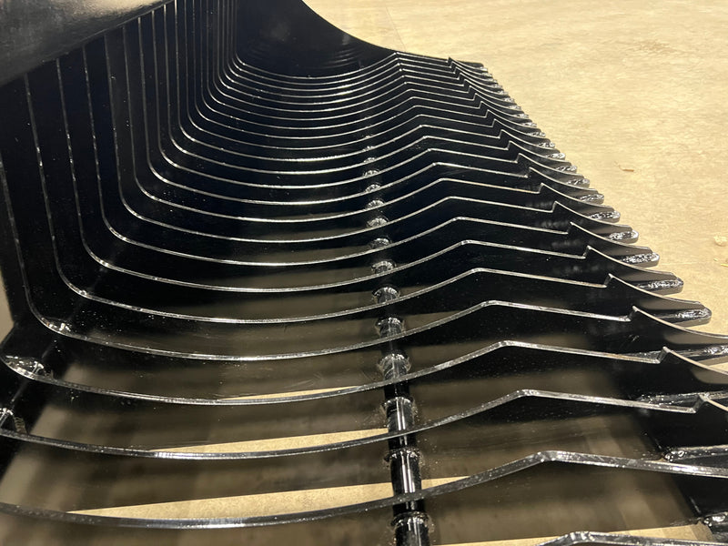 Close up Stinger Attachments of the black tractor rock bucket edges