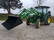 Side angle of green John Deer tractor with black tractor rock bucket Stinger Attachment